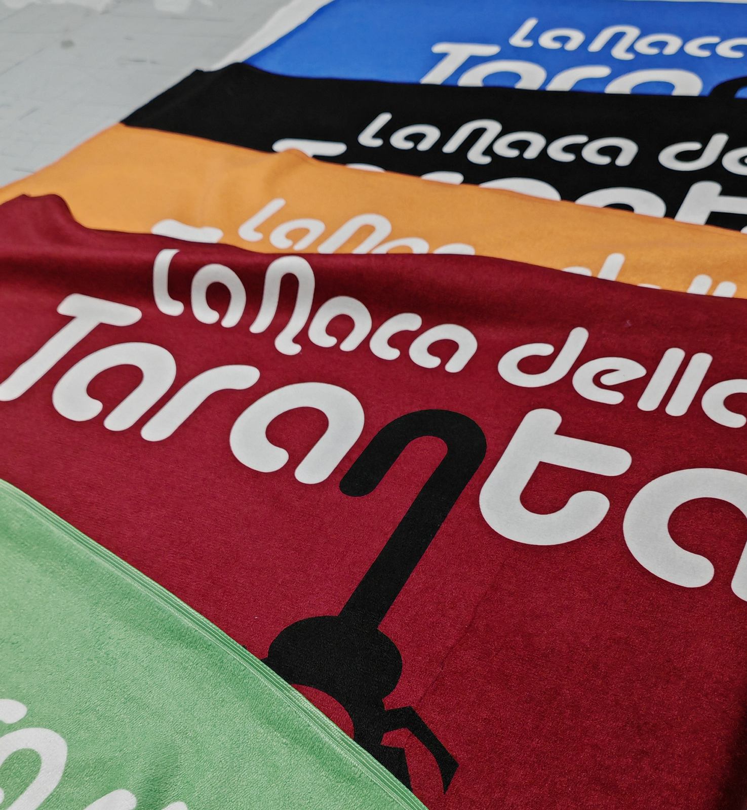 Asciugamani personalizzati in sublimazione nei colori blu, nero, arancio, bordeaux e verde per una struttura ricettiva del Salento