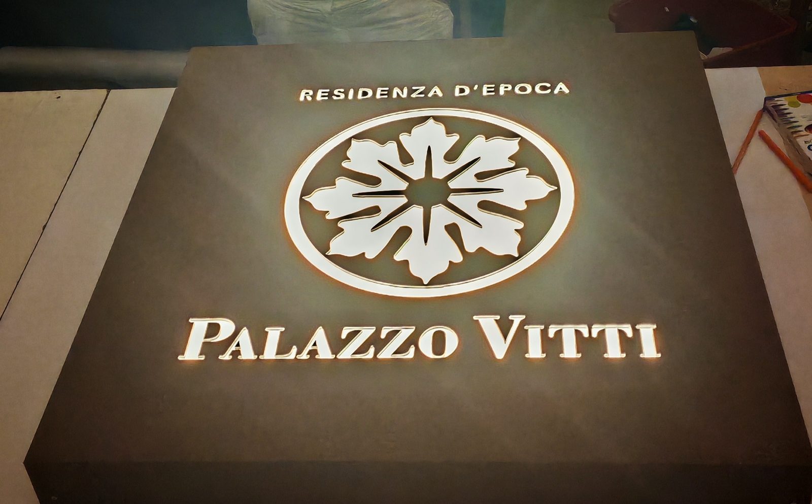 Insegna luminosa Palazzo Vitti accesa nella reception di una dimora storica