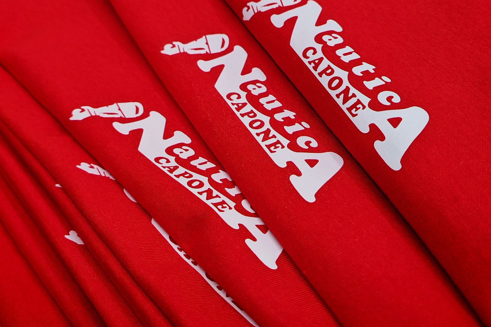 Pila di magliette da lavoro rosse personalizzate per lo staff di Nautica Capone