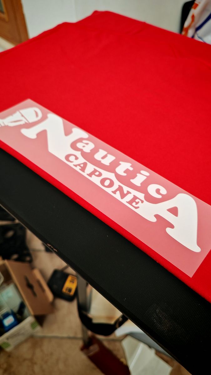 Applicazione del logo su una maglietta da lavoro rossa nel laboratorio di stampa a Lecce