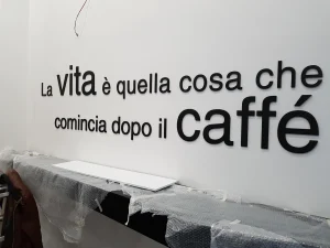 Frase in lettere 3D nere su parete bianca, nel bar in allestimento