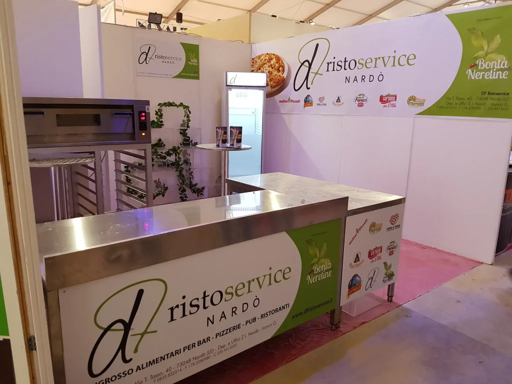 Stand fieristico con bancone in acciaio e pareti stampate, pronto prima dell'apertura