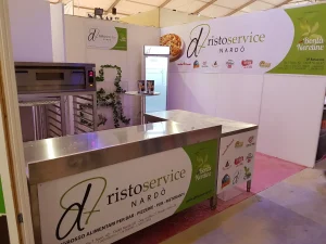 Stand fieristico con bancone in acciaio e pareti stampate, pronto prima dell'apertura