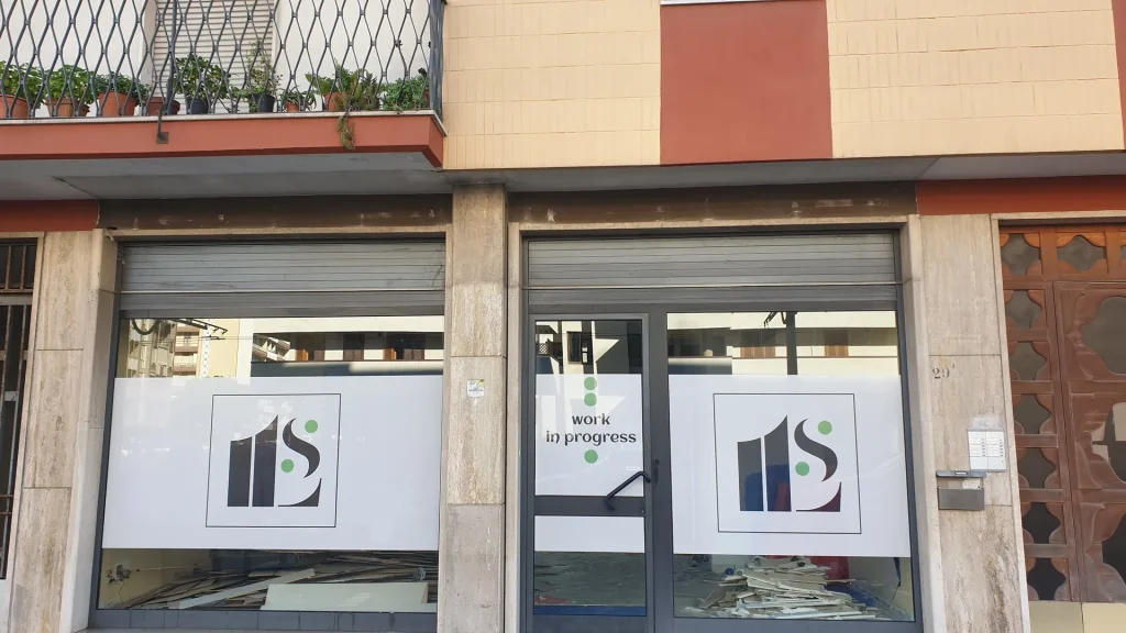 Vetrine di un locale in allestimento coperte con carta stampata con il logo e la scritta work in progress